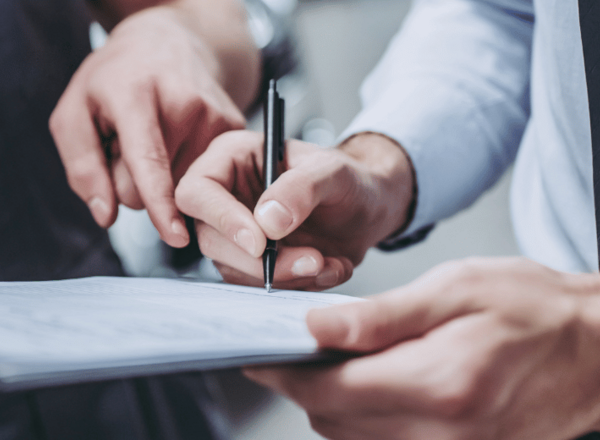 Zwei Personen füllen gemeinsam ein Formular auf einem Klemmbrett aus