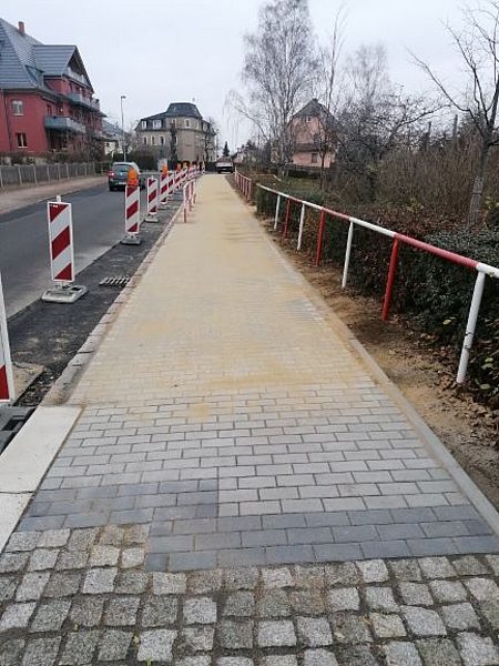 Neu gepflasterter Gehweg mit Absperrungen – Straßenbau und Gehwegerneuerung in Wohngebiet