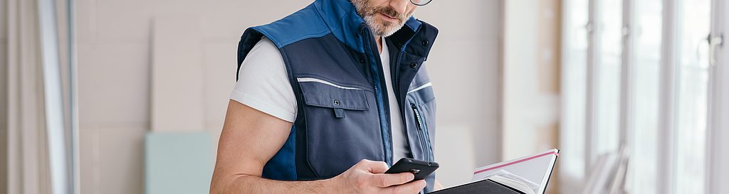 Afbeelding van een vakman met een mobiele telefoon en een notitieblok