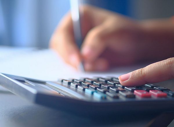 Close-up van een hand die op een rekenmachine typt